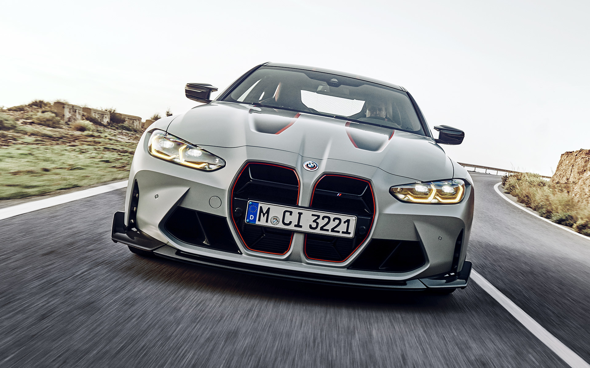 Juodos priekinės grotelės su raudonos spalvos modelio ženklinimu BMW M4 CSL G82 BMW M4 CSL G82 BMW Individual pilkos Frozen Brooklyn Grey metalizuotos spalvos, juodos priekinės grotelės su raudonos spalvos modelio ženklinimu, gatve važiuojančio automobilio vaizdas iš priekio