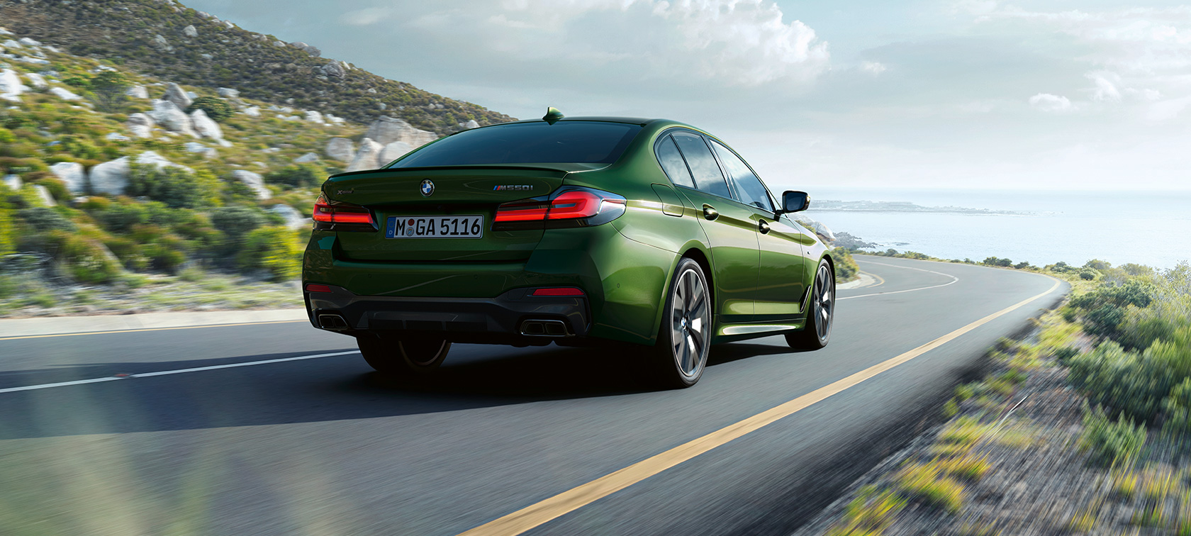 BMW M550i xDrive sedanas G30 LCI Facelift 2020, važiuojančio automobilio trijų ketvirčių vaizdas iš galo BMW M550i xDrive sedanas G30 LCI Facelift 2020, BMW Individual žalio Verde Ermes metaliko spalvos, važiuojančio automobilio trijų ketvirčių vaizdas iš galo