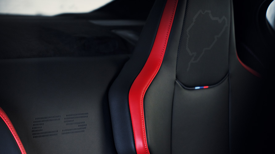 BMW M5 CS F90 2021 interjeras, išgaubta M Carbon anglies pluošto sėdynė su apšviestu M5 logotipu ir Niurburgringo kontūrais