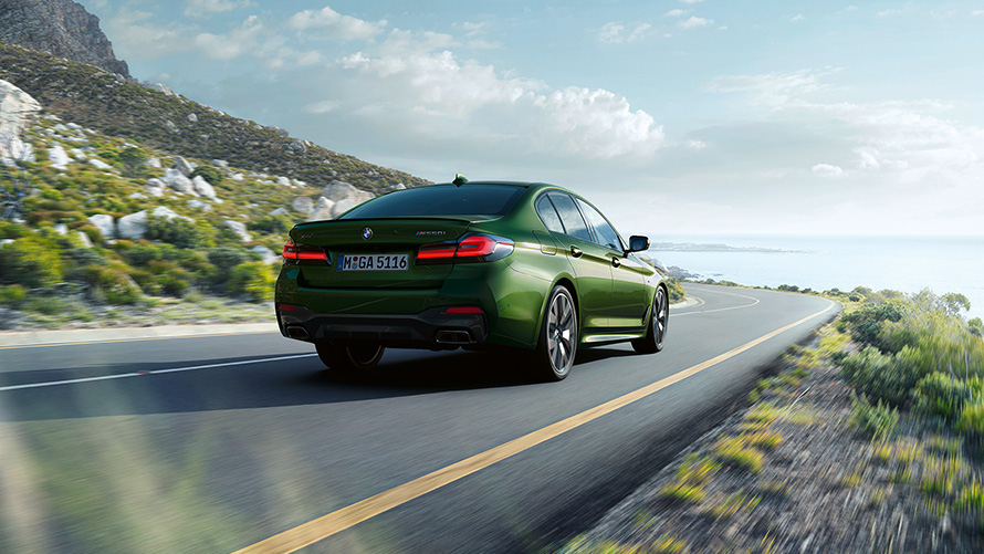 BMW M550i xDrive sedanas G30 LCI Facelift 2020 BMW Individual „Verde Ermes“ metaliko spalvos, važiuojančio automobilio trijų ketvirčių vaizdas iš galo