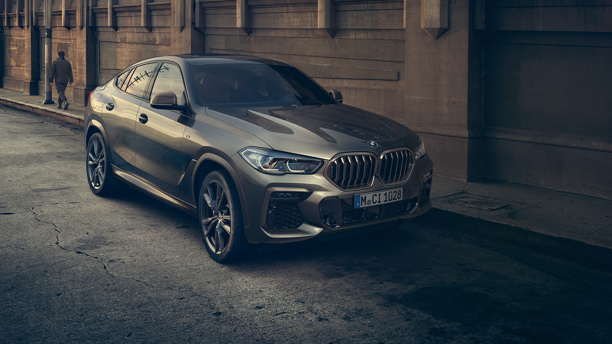 Stovintis BMW X6 M50i Stovinčio BMW X6 M50i trijų ketvirčių vaizdas iš priekio miesto fone