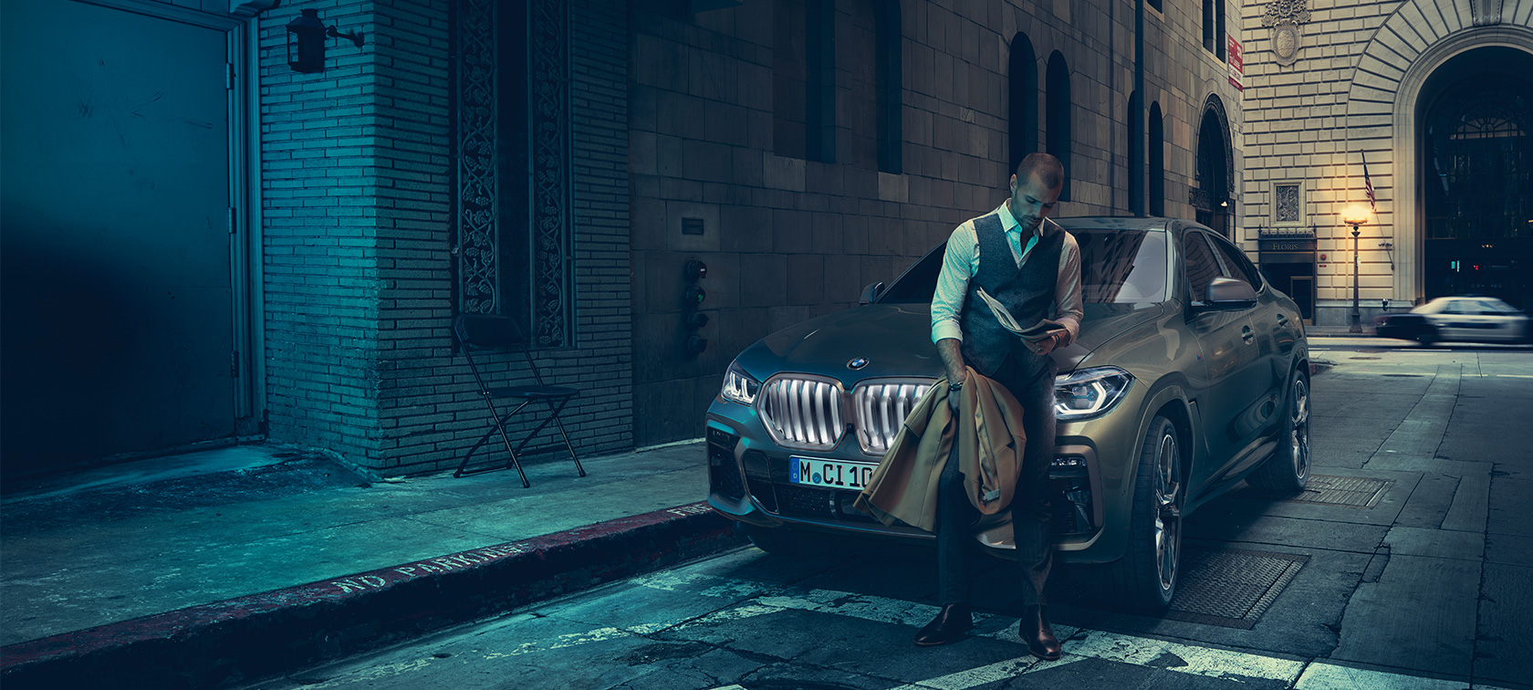 BMW X6 M50i priekis Vyras atsirėmęs į BMW X6 M50i priekį
