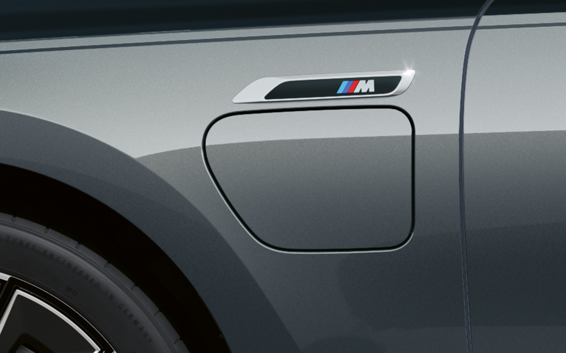 M ženklelis BMW M760e xDrive sedanas G70 M Performance paketas BMW Individual dviejų atspalvių Black Sapphire juoda metalizuota dažų apdaila BMW Individual Dravite Grey pilka metalizuota spalva priartintas vaizdas iš šono