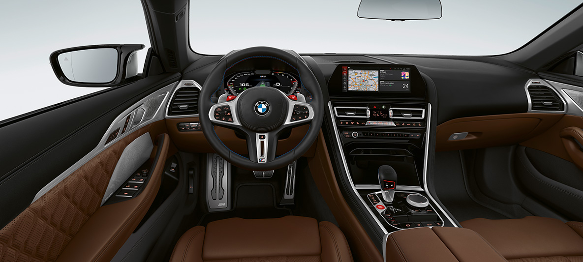 BMW M8 kabrioletas, vairuotojo erdvė. BMW M8 kabrioleto vairuotojo erdvė M odiniu vairu M1/M2 raudonais mygtukais.