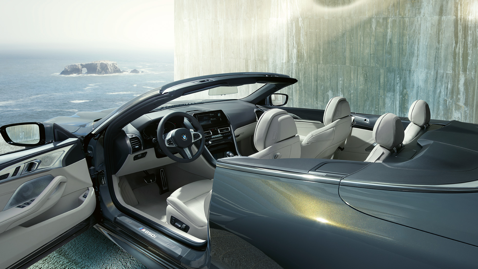 BMW M850i xDrive kabrioletas, interjeras. BMW M850i xDrive kabrioletas Dravit Grey pilko metaliko spalvos su atviru minkštu stogu, interjeras su M odiniu vairu ir BMW Individual Merino Ivory White dramblio kaulos spalvos odos apdaila.
