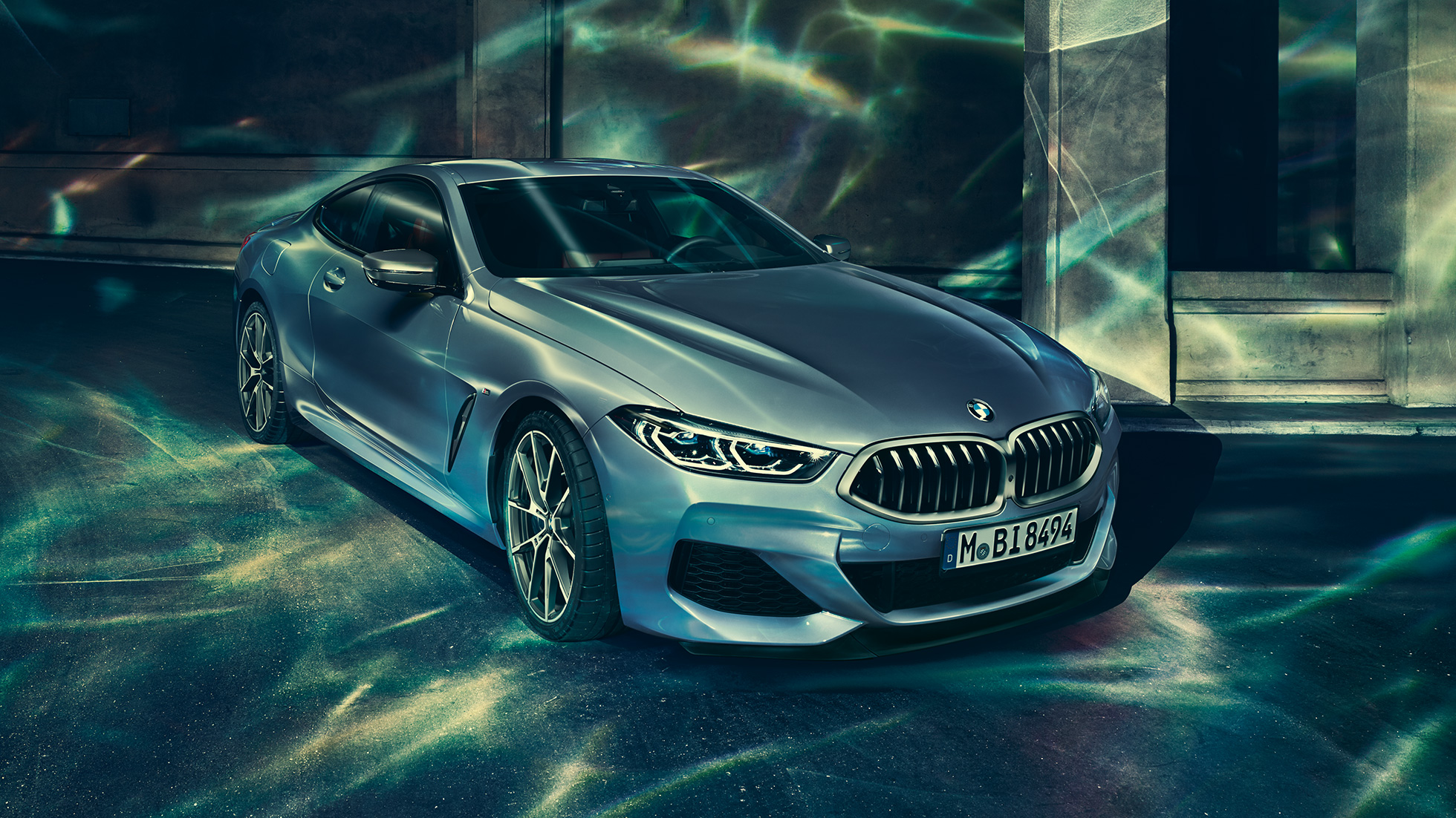 BMW M850i xDrive Coupé, trijų ketvirčių vaizdas iš priekinės dešinės pusės BMW M850i xDrive kupė Barcelona Blue mėlyno metaliko spalvos, trijų ketvirčių priešais pastatą stovinčio automobilio vaizdas iš priekinės dešinės pusės