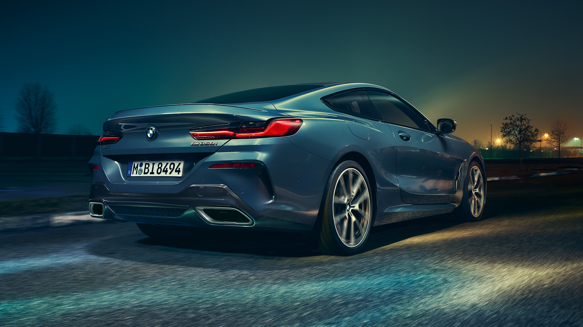 BMW M850i xDrive kupė, vaizdas iš galo BMW M850i xDrive kupė Barcelona Blue mėlyno metaliko spalvos, naktį važiuojančio automobilio vaizdas iš galo