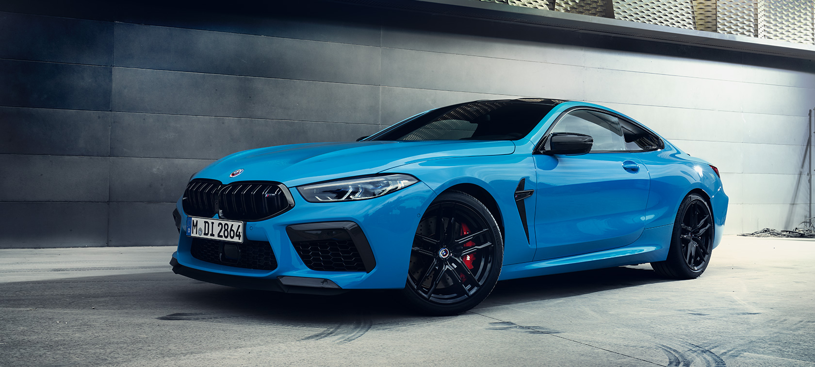BMW M8 Competition kupė F92 LCI Facelift 2022 mėlynos Daytona Beach Blue spalvos sienos fone stovinčio automobilio trijų ketvirčių vaizdas iš šono