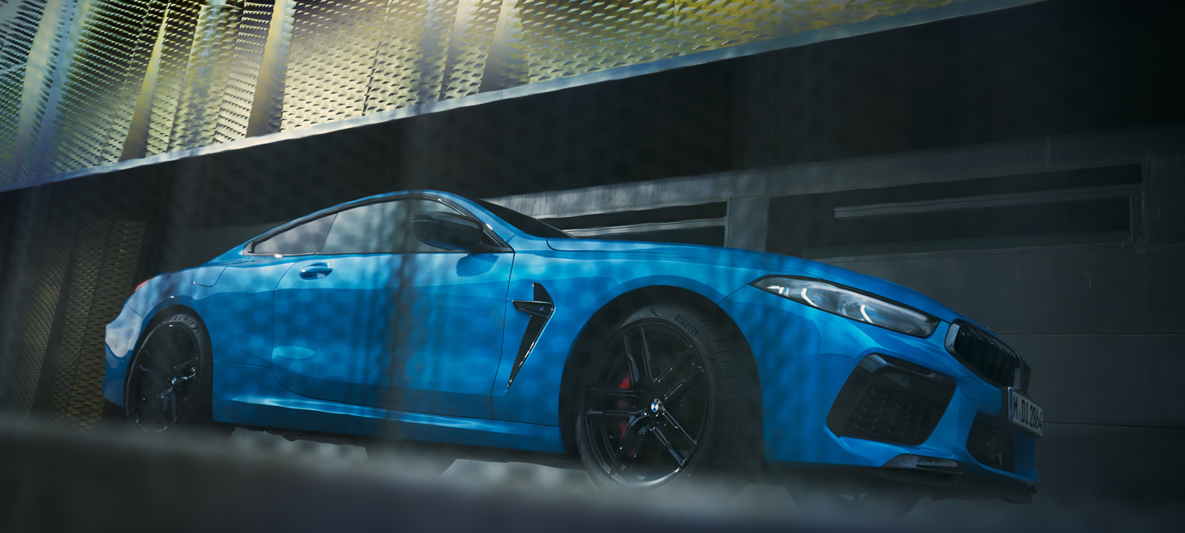 BMW M8 Competition kupė F92 LCI Facelift 2022 stovinčio automobilio vaizdas iš šono žemu kampu BMW M8 Competition kupė F92 LCI Facelift 2022 metalizuotos mėlynos BMW Individual Daytona Beach Blue spalvos pastato fone stovinčio automobilio vaizdas žemu kampu