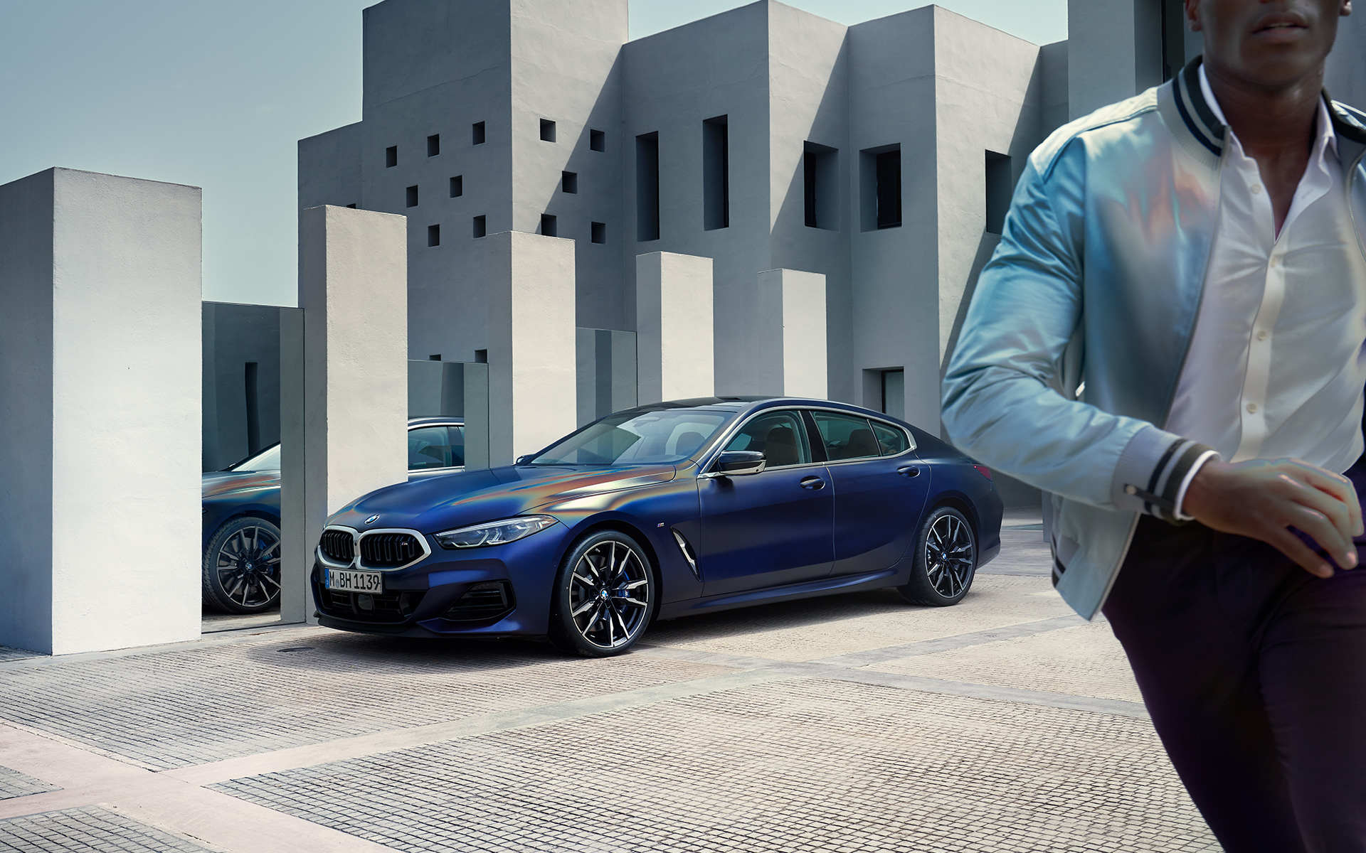 Trijų ketvirčių vaizdas iš priekio BMW M850i xDrive Gran kupė G16 LCI Facelift 2022 BMW M850i xDrive Gran kupė G16 LCI Facelift 2022 BMW Individual metalizuotos Frozen Tanzanite Blue mėlynos kėbulo spalvos trijų ketvirčių vaizdas iš priekio su stovinčiu vyru modeliu priešakyje