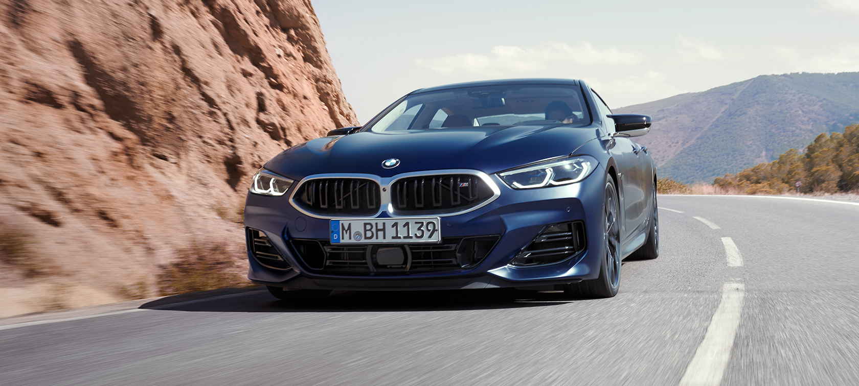 Trijų ketvirčių vaizdas iš priekio keliu važiuojantis BMW M850i xDrive Gran kupė G16 LCI Facelift 2022 BMW M850i xDrive Gran kupė G16 LCI Facelift 2022 BMW Individual metalizuotos Frozen Tanzanite Blue mėlynos kėbulo spalvos posūkyje važiuojančio automobilio trijų ketvirčių vaizdas iš priekio