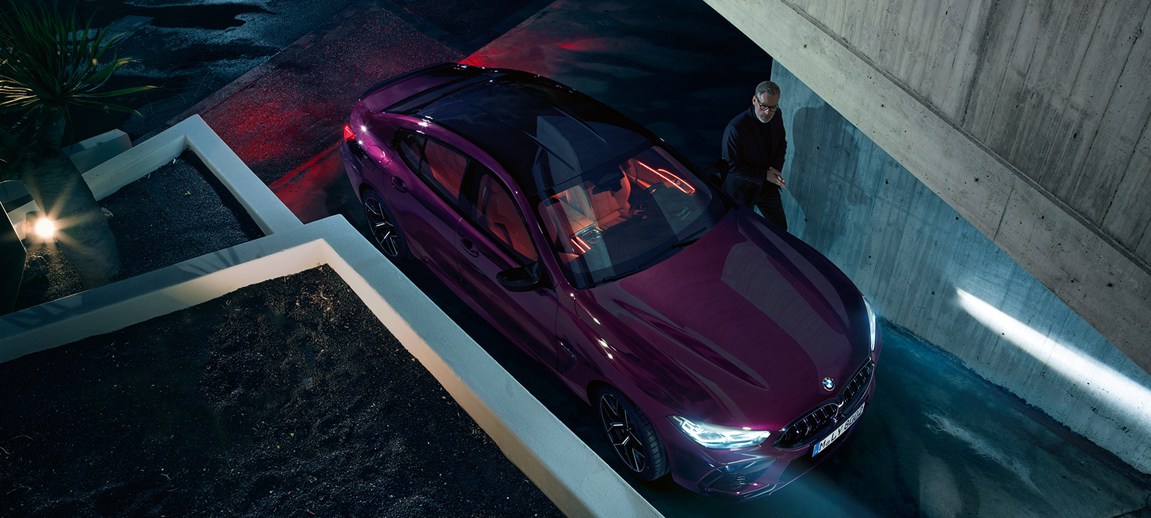 BMW M8 Competition Gran kupė BMW vaizdas iš paukščio skrydžio Pastato fone stovinčio BMW M8 Competition Gran kupė BMW Individual Ametrine metaliko spalvos trijų ketvirčių vaizdas iš paukščio skrydžio