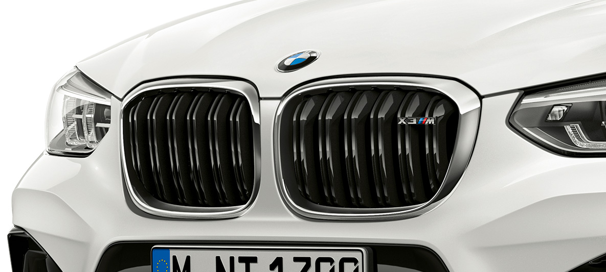 BMW X3 M, M priekinės grotelės. BMW X3 M „Alpine White“ baltos spalvos, eksterjeras, priekis, M priekinės grotelės su chromo akcentais ir modelio ženkleliu