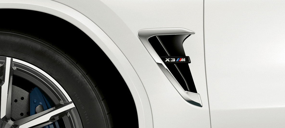 BMW X3 M, M šoninė oro anga. BMW X3 M „Alpine White“ baltos spalvos, eksterjeras, M šoninė oro anga su chromo akcentais ir modelio ženkleliu