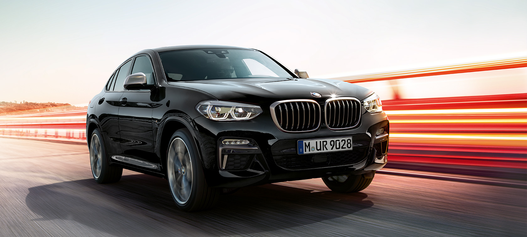 BMW X4 M40i ir BMW X4 M40d, trijų ketvirčių vaizdas iš priekio, kairė pusė. BMW X4 M40i ir BMW X4 M40d „Black Sapphire“ juodo metaliko spalvos, eksterjeras, apšviestas trijų ketvirčių vaizdas iš priekio kairės pusės.