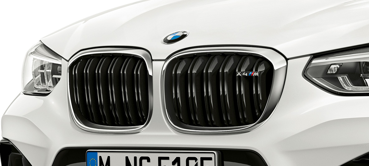 BMW X4 M, M priekinės grotelės. BMW X4 M „Alpine White“ baltos spalvos, eksterjeras, priekis, M priekinės grotelės su chromo akcentais ir modelio ženkleliu.