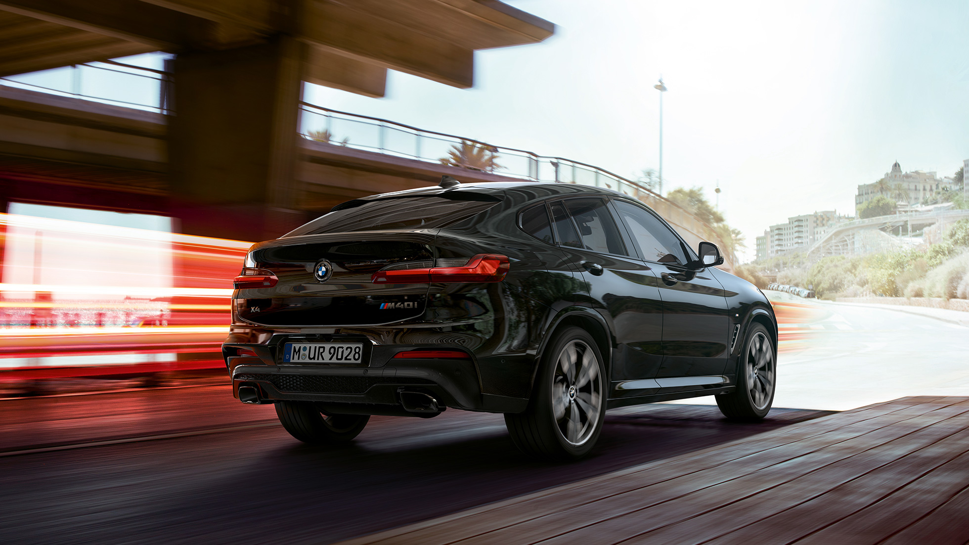 BMW X4 M40i, trijų ketvirčių vaizdas iš priekio. BMW X4 M40i „Black Sapphire“ juodo metaliko spalvos, važiuojantis keliu, eksterjeras, apšviestas trijų ketvirčių vaizdas iš priekio.