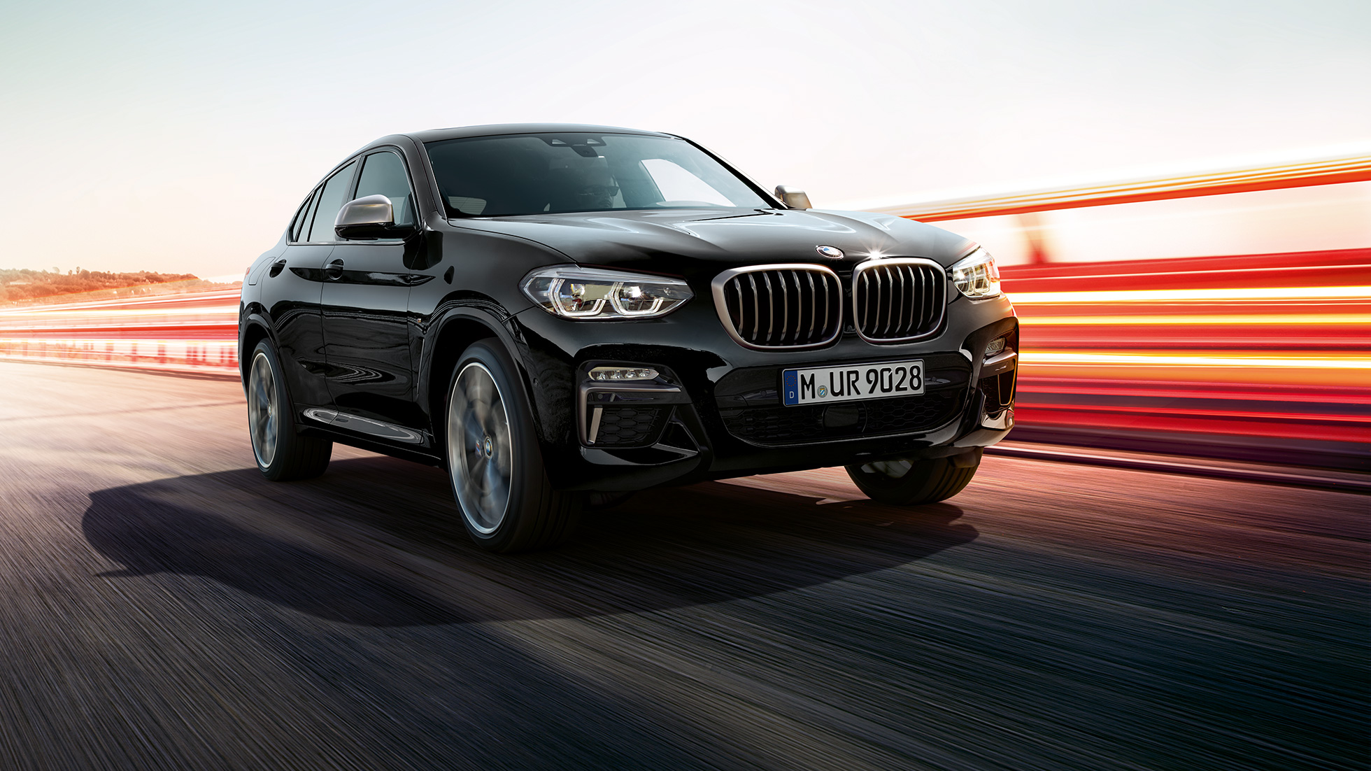 BMW X4 M40i ir BMW X4 M40d, trijų ketvirčių vaizdas iš priekio. BMW X4 M40i ir BMW X4 M40d „Black Sapphire“ juodo metaliko spalvos, eksterjeras, trijų ketvirčių vaizdas iš priekio, apšviesta kairė pusė.