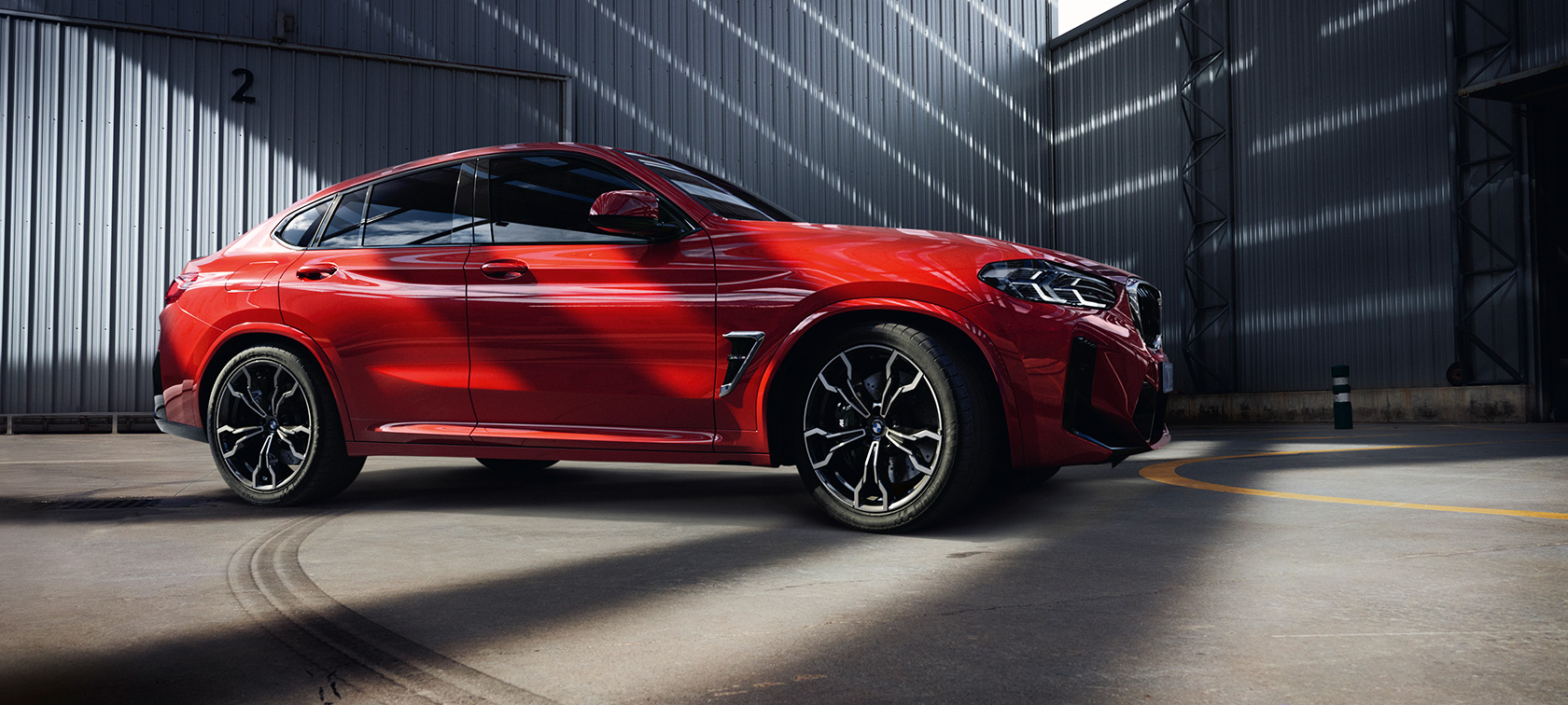 BMW X4 M (F98) LCI Facelift 2021 trijų ketvirčių vaizdas iš priekio BMW X4 M (F98) LCI Facelift 2021 raudonos metalizuotos Toronto Red kėbulo spalvos trijų ketvirčių vaizdas iš priekio gamyklos viduje