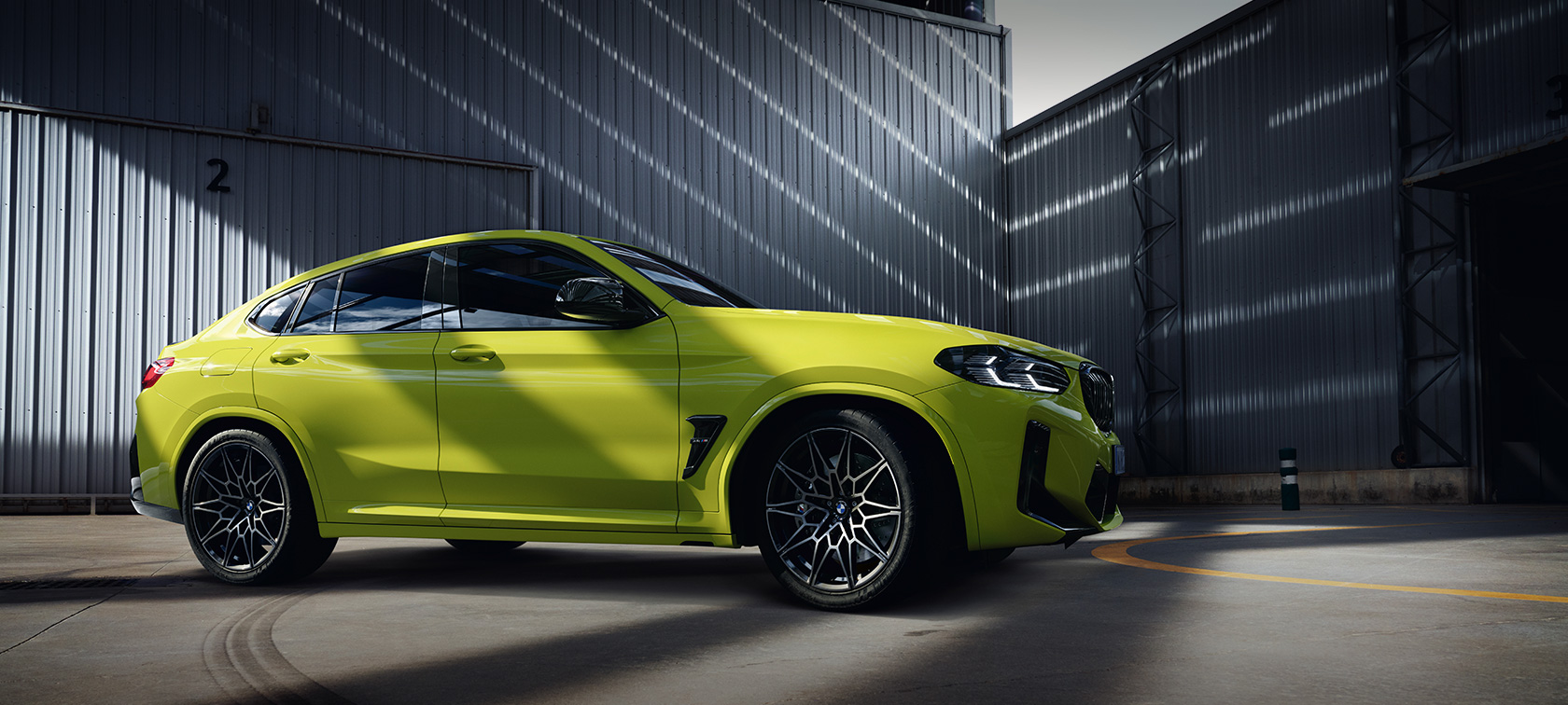 BMW X4 M Competition (F98) LCI Facelift 2021 geltonos Sao Paulo Yellow spalvos vaizdas iš šono aikštėje
