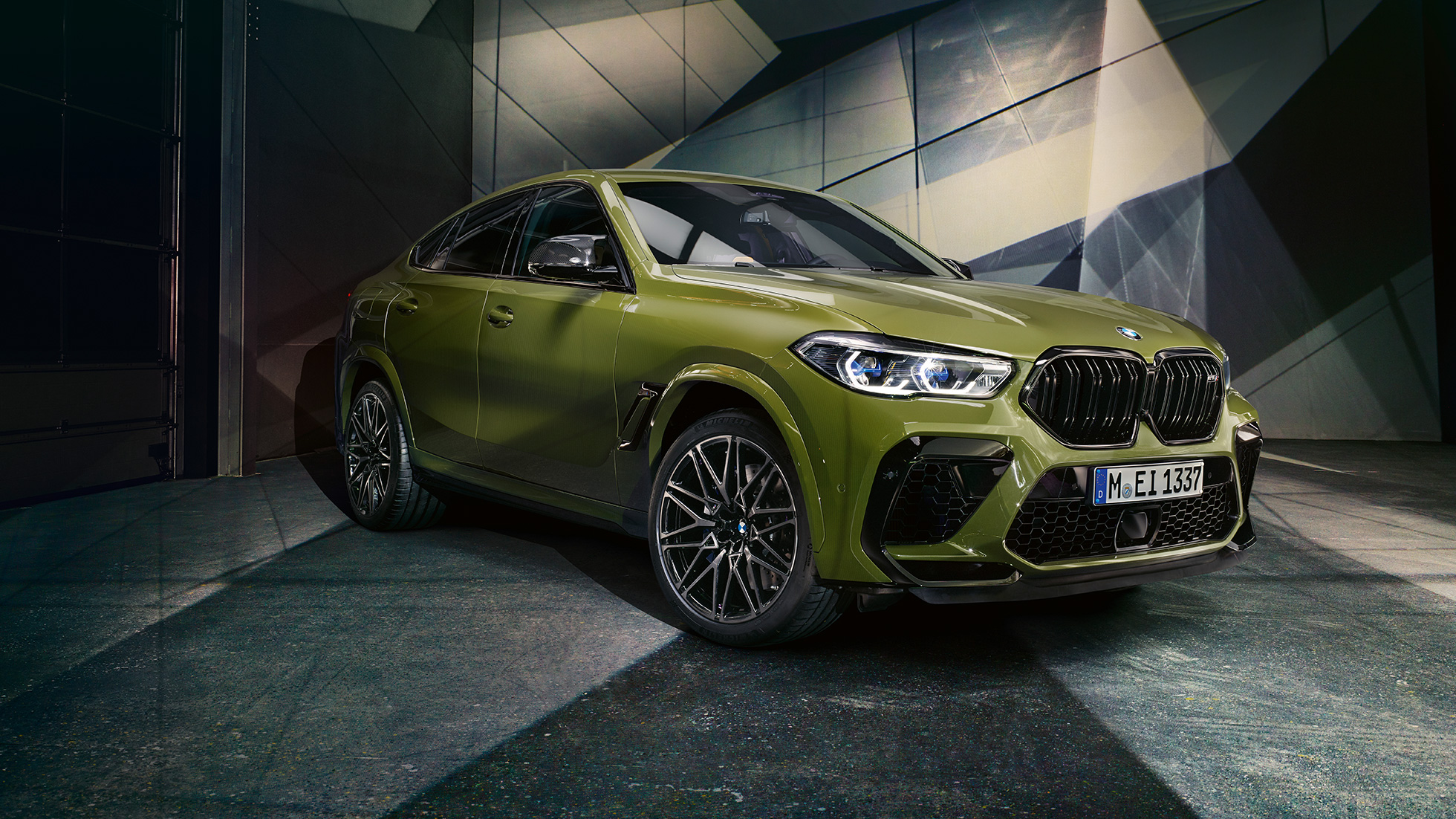 BMW X6 M Competition M dvigubos priekinės grotelės BMW X6 M Competition F96 M dvigubos priekinės grotelės, SUV su BMW Individual specialia Urban Green dažų apdaila, trijų ketvirčių vaizdas iš priekio