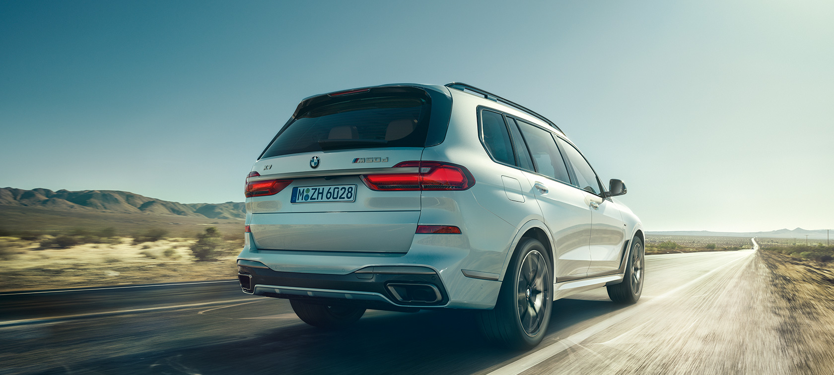 BMW X7 M50d, vaizdas iš galo BMW X7 M50d tuščiu greitkeliu važiuojančio Mineral White baltos spalvos automobilio vaizdas iš galo, G07, 2019