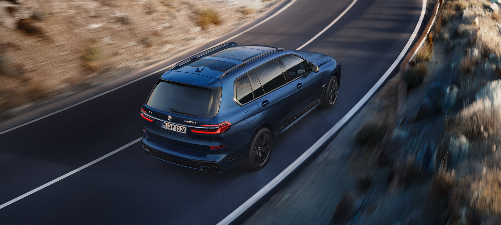 BMW X7 M60i xDrive G07 LCI mėlynos Frozen Marina Bay Blue spalvos, važiuojančio automobilio trijų ketvirčių galinis vaizdas iš paukščio skrydžio BMW X7 M60i xDrive G07 LCI mėlynos Frozen Marina Bay Blue spalvos, gatve važiuojančio automobilio trijų ketvirčių galinis vaizdas iš paukščio skrydžio