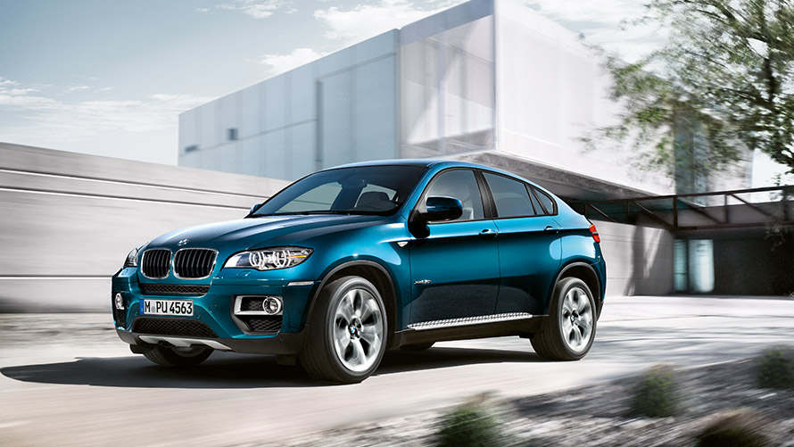BMW X6 (E71) pirmoji karta, pastato fone stovinčio automobilio trijų ketvirčių vaizdas iš šono BMW X serijos BMW X6 (E71) pirmoji karta, pastato fone stovinčio automobilio trijų ketvirčių vaizdas iš šono