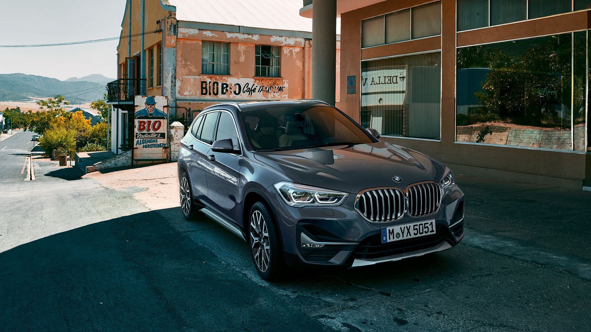 BMW X1, trijų ketvirčių vaizdas iš priekio. BMW X1, miesto fone stovinčio automobilio trijų ketvirčių vaizdas iš priekio.