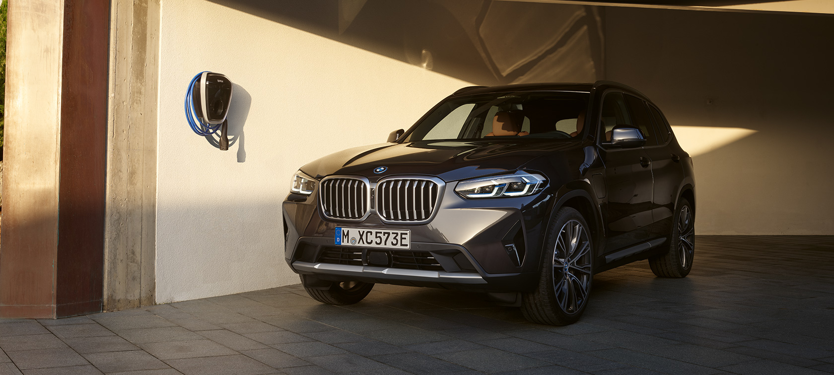 Įkraunamas hibridinis BMW X3 xDrive30e (G01) pilkos Sophisto Grey spalvos 2021 Įkraunamas hibridinis BMW X3 xDrive30e (G01) pilkos Sophisto Grey spalvos, stovinčio automobilio trijų ketvirčių vaizdas iš priekio 2021