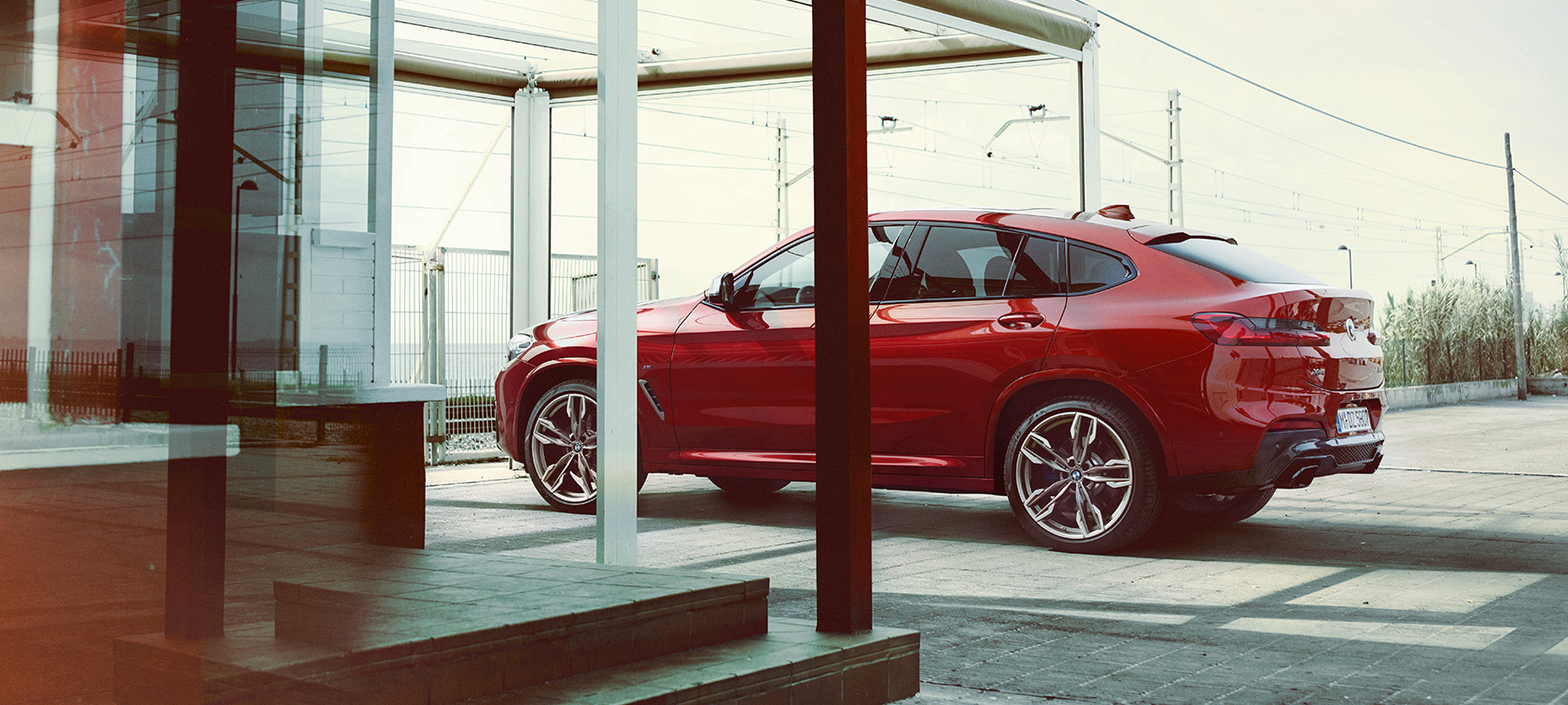 BMW X4 vaizdas iš šono BMW X4 M40i G02 2018 Flamenco Red brilliant effect tviskančios raudonos spalvos automobilio vaizdas iš šono stovėjimo aikštelėje