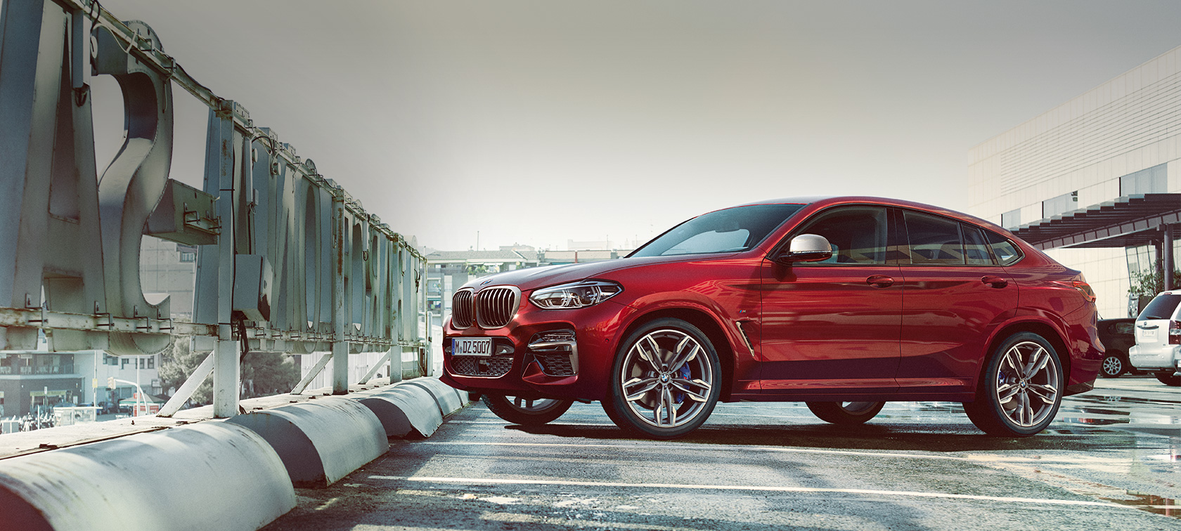 BMW X4 vaizdas iš šono parkuojantis BMW X4 M40i G02 2018 Flamenco Red brilliant effect tviskančios raudonos spalvos parkuojamo aikštelėje automobilio vaizdas iš šono