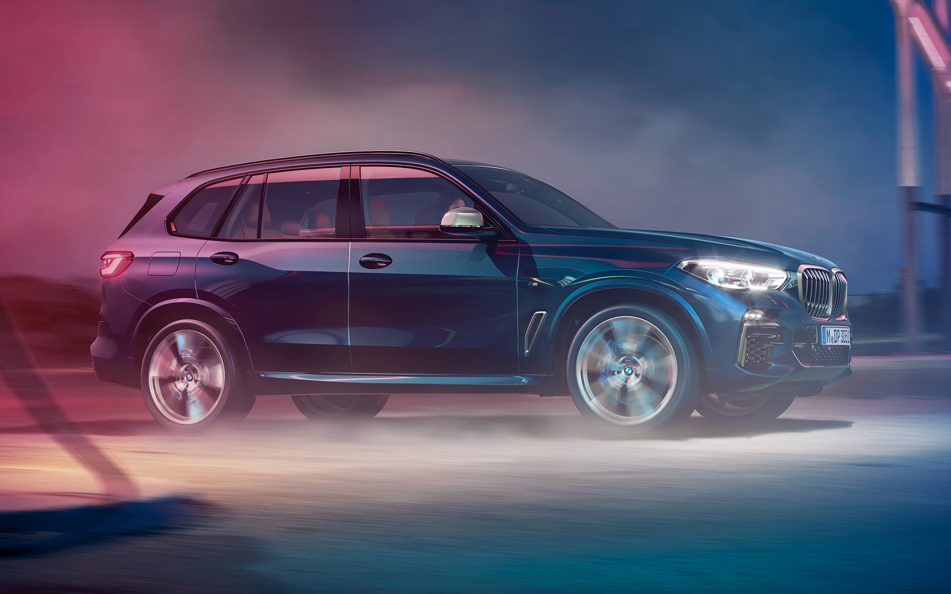 BMW X5 M50d judesy BMW X5 M50d, riedančio naktį urbanistinio peizažo fone, nuotrauka
