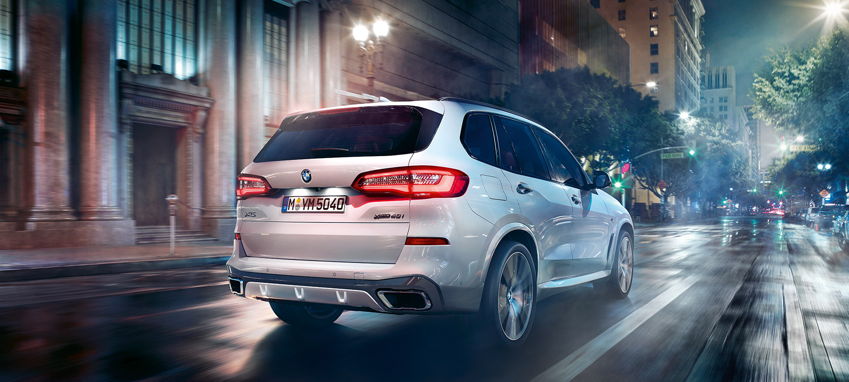 BMW X5 važiuojančio automobilio trijų ketvirčių vaizdas iš galo BMW X5 G05 2018 Mineral White balto metaliko spalvos naktį važiuojančio automobilio trijų ketvirčių vaizdas iš galo