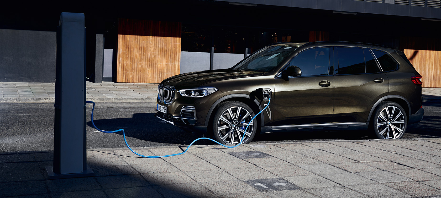 Įkraunamas hibridinis BMW X5 xDrive45e (G05), trijų ketvirčių vaizdas iš priekio Įkraunamas hibridinis BMW X5 xDrive45e (G05), įkraunamo automobilio trijų ketvirčių vaizdas iš šono