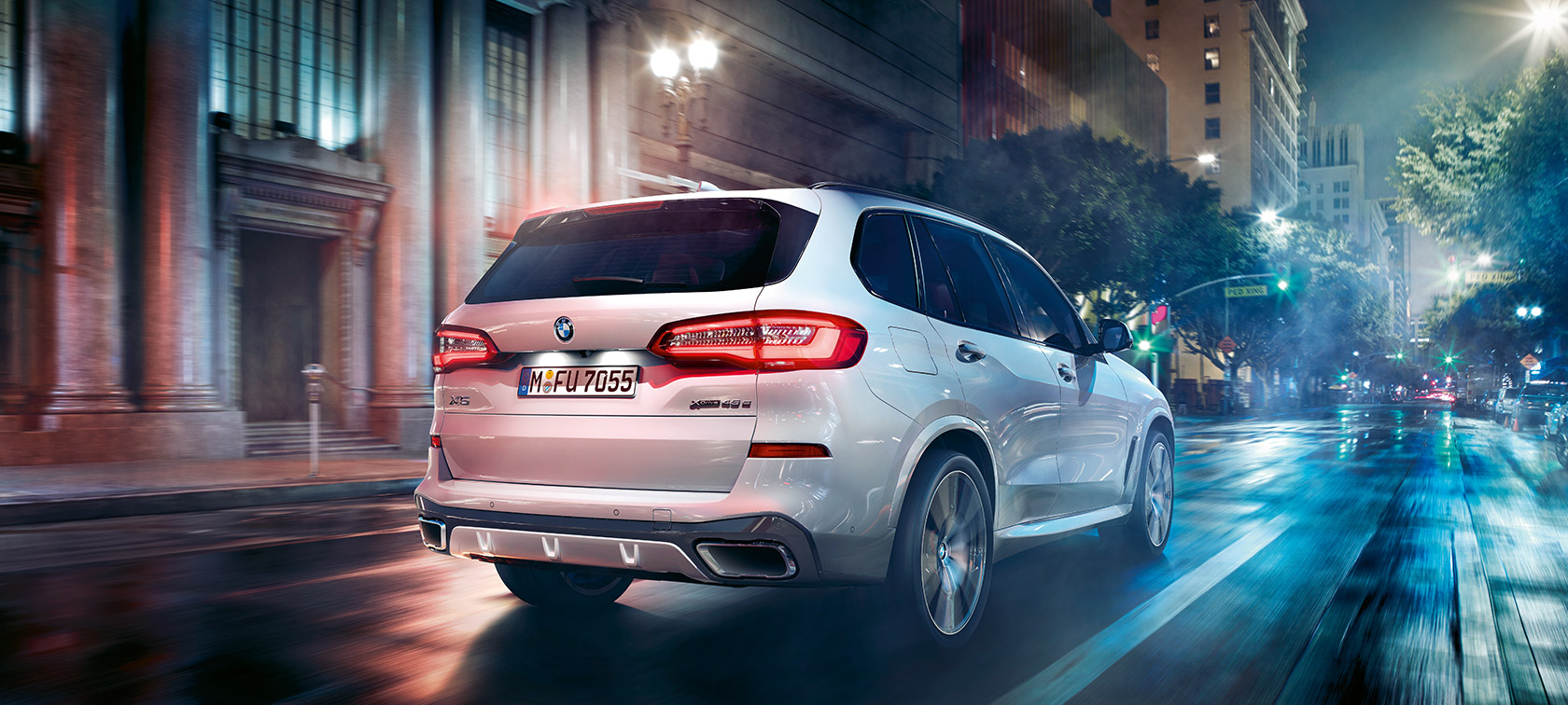Važiuojančio keliu BMW X5 trijų ketvirčių vaizdas iš galo BMW X5 G05 2018 baltos metalizuotos <i>Mineral White</i> spalvos, važiuojančio automobilio trijų ketvirčių vaizdas iš galo