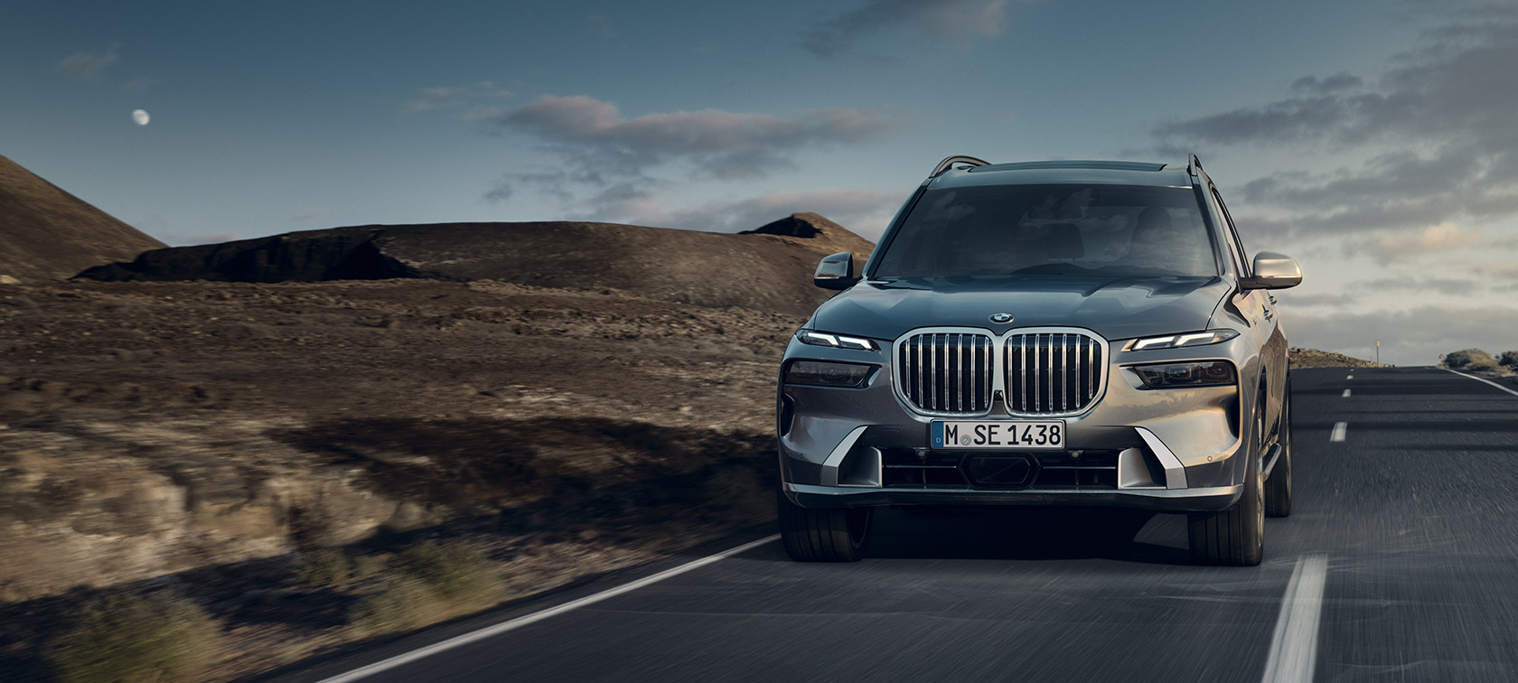 BMW X7 G07 LCI 7/8 važiuojančio automobilio vaizdas iš priekio pilkos metalizuotos Sparkling Copper Grey spalvos Design Pure Excellence