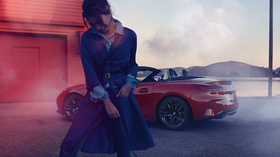 BMW Z4 Roadster G29 su atviru stogu BMW Z4 M40i Roadster G29 trijų ketvirčių vaizdas iš galo su atviru stogu ir moterimi priešakyje