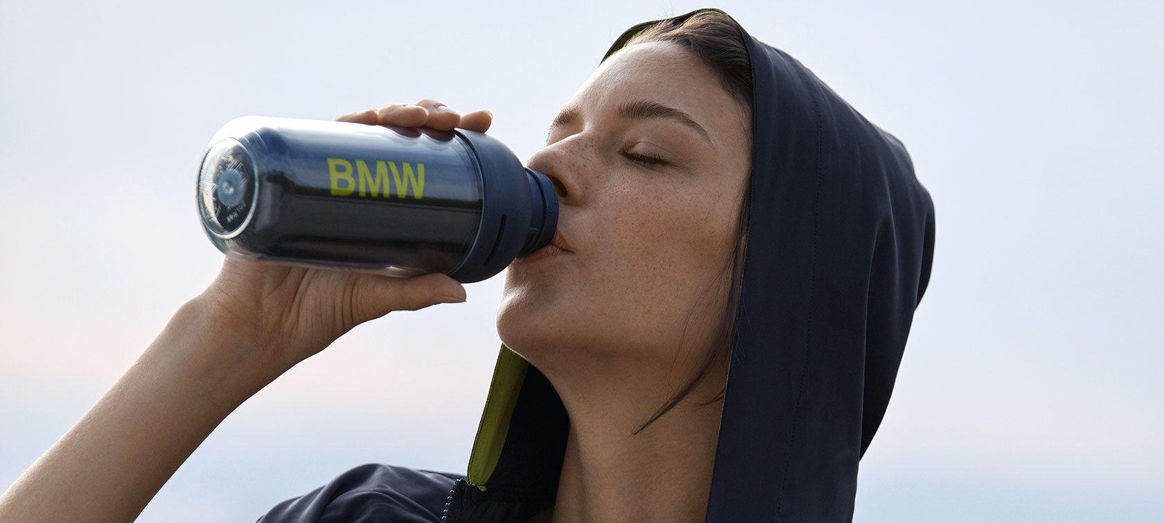 BMW Active sportinis buteliukas. Nuotraukoje moteris, gerianti iš BMW Active sportinio buteliuko.