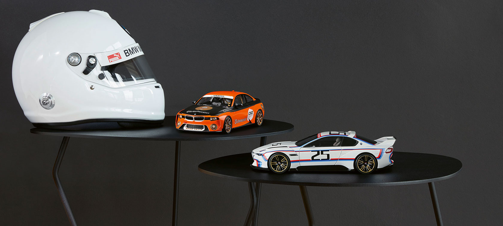 Nuotraukoje - BMW 2002 Homage Turbomeister miniatiūra ir BMW 3.0 CSL 25 miniatiūra, padėtos dešinėje, prie balto šalmo. Nuotraukoje - BMW 2002 Homage Turbomeister miniatiūra ir BMW 3.0 CSL 25 miniatiūra, padėtos dešinėje, prie balto šalmo.