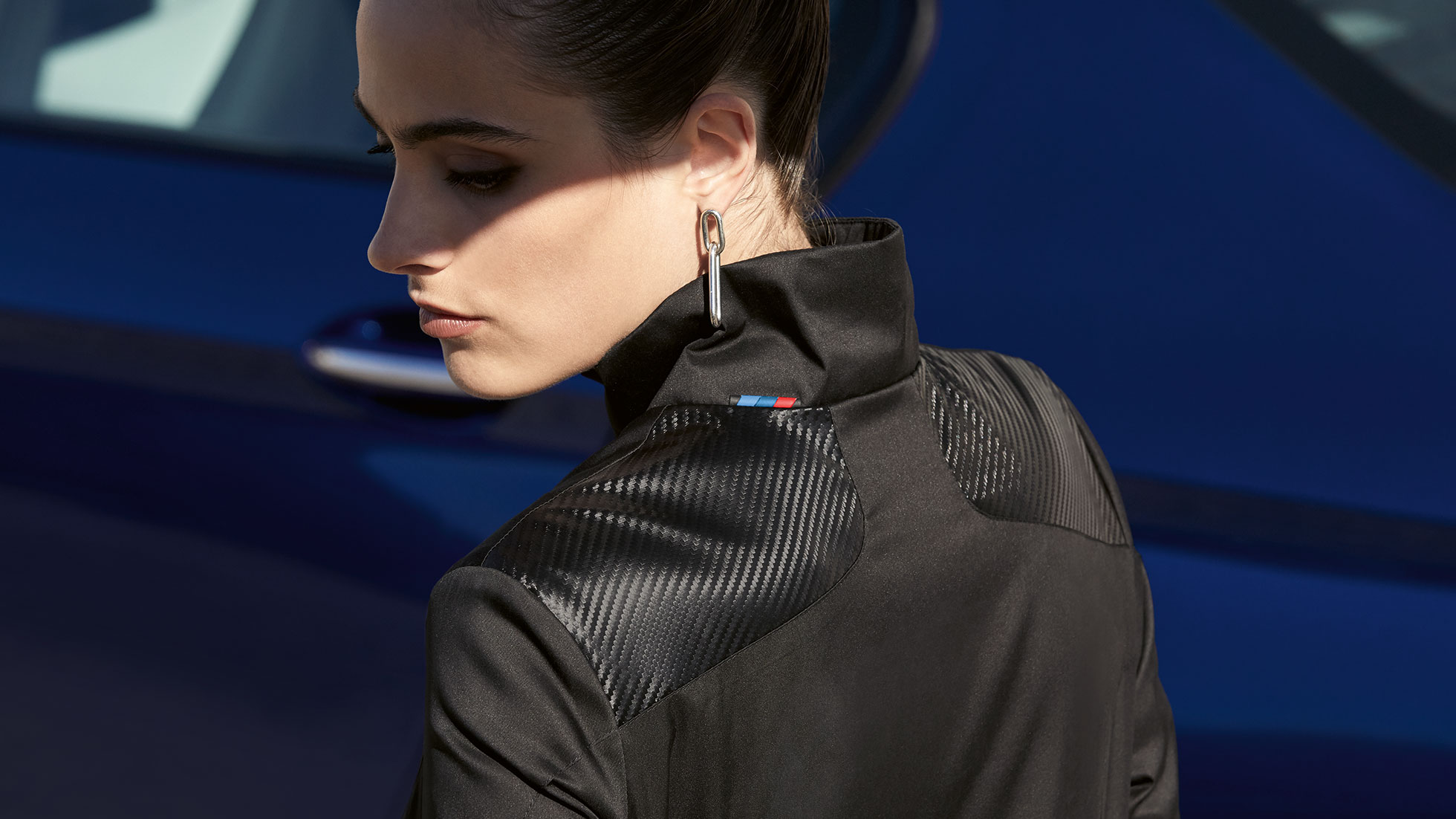 BMW M moteriška striukė Pro petį žvelgia jauna mergina modelis, vilkinti BMW M moterišką striukę.