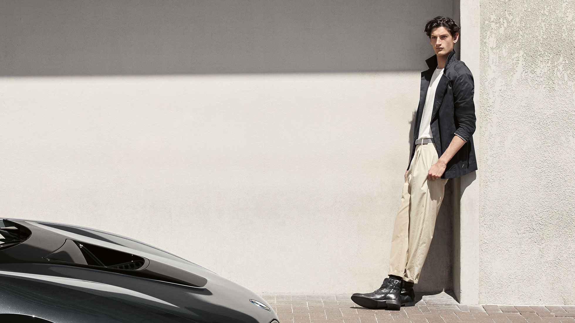 BMW i Collection Nuotraukoje į sieną atsirėmęs vyras su BMW i striuke iš BMW i Collection