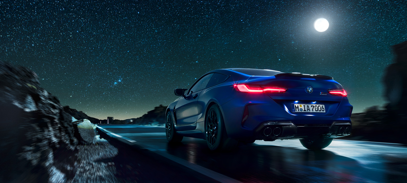 BMW M8 Competition kupė, vaizdas iš galo BMW M8 Competition kupė, mėnesienos fone važiuojančio automobilio vaizdas iš galo
