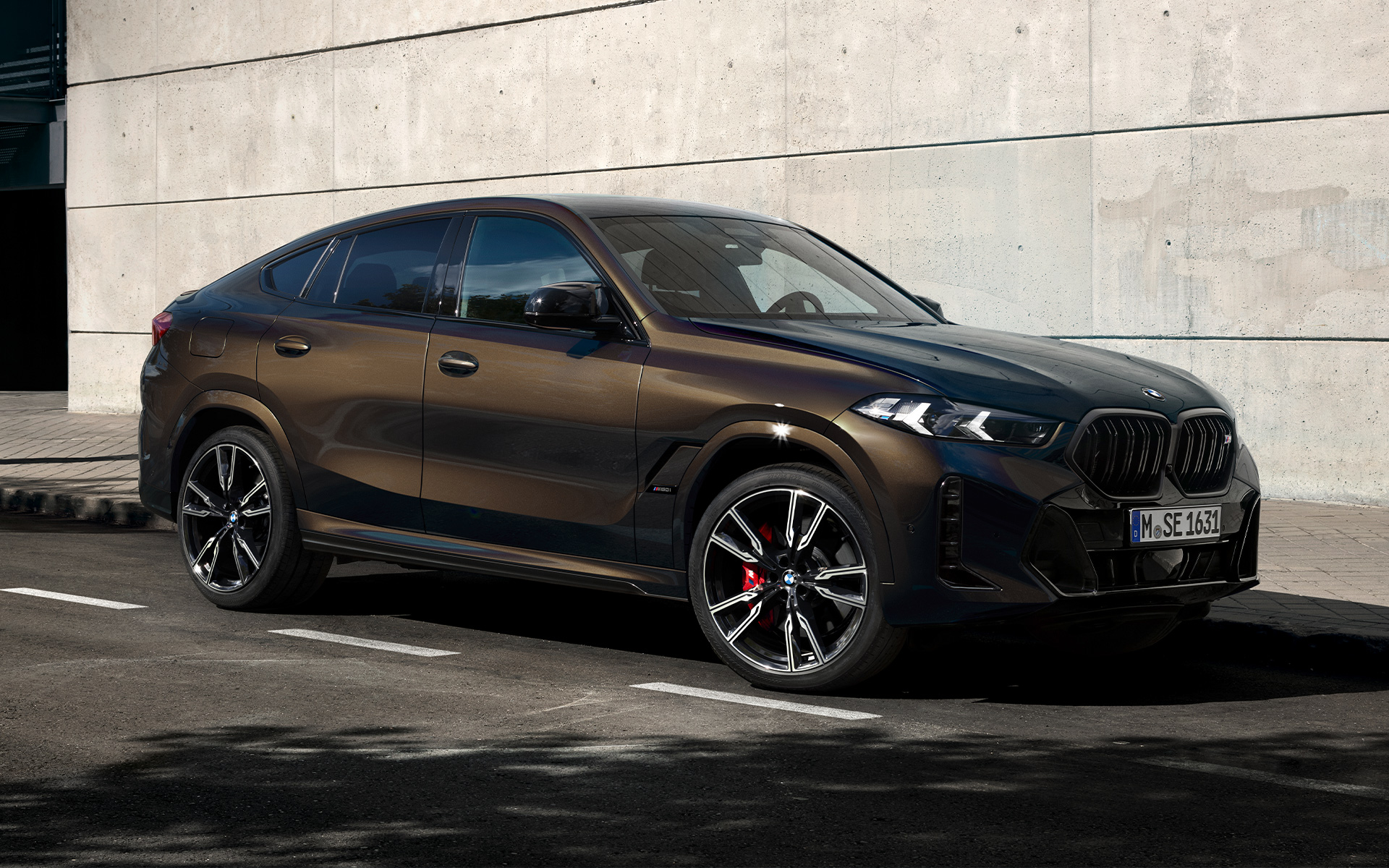 BMW X6 M60i G06 Pyrite Brown rudos metalizuotos spalvos BMW X6 M60i G06 BMW Individual Pyrite Brown rudos metalizuotos spalvos, 2/3 vaizdas iš šono, stovėjimo aikštelėje stovintis automobilis
