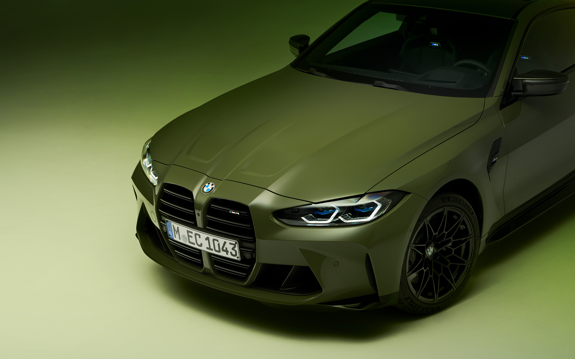 BMW M4 Competition kupė (G82) 2021 BMW Individual žalios Urban Green spalvos, trijų ketvirčių vaizdas iš priekio BMW M4 Competition kupė (G82) 2021 BMW Individual žalios Urban Green spalvos, automobilio trijų ketvirčių priekinis vaizdas iš viršaus