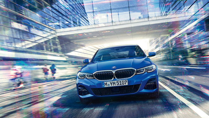 Važiuojančio mėlyno BMW nuotrauka Važiuojančio mėlyno BMW nuotrauka. Fone – įstiklintas pėsčiųjų tiltas