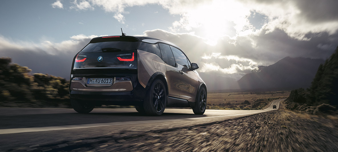 BMW i3s kalnų fone BMW nuvažiuojamo atstumo pavyzdys BMW i3s kalnų fone trijų ketvirčių vaizdas iš galo kalnų fone