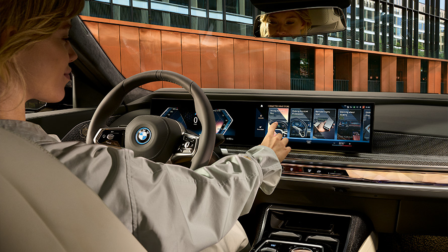 Užsakomosios funkcijos BMW ConnectedDrive užsakomosios funkcijos BMW sėdinti moteris naudojasi jutikliniu ekranu