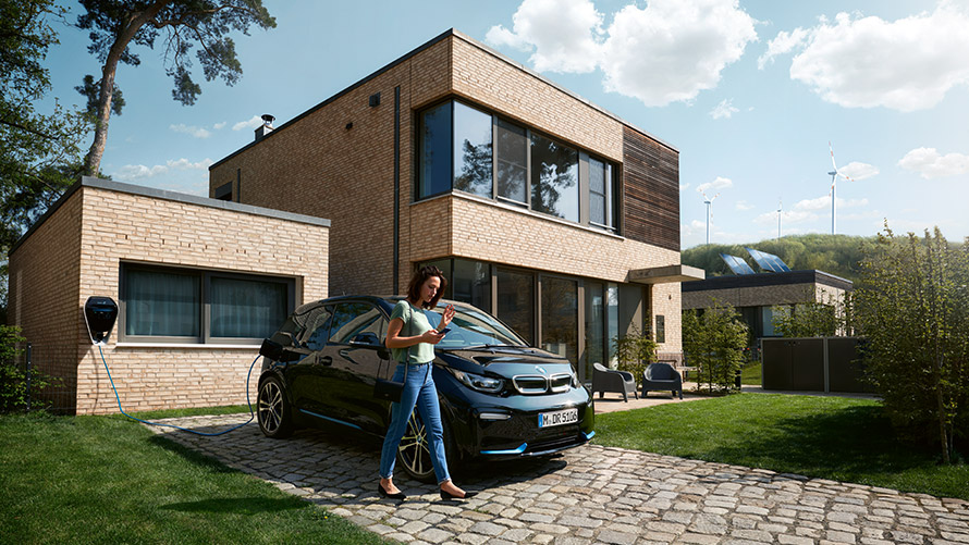 Skaitmeninio įkrovimo funkcija Moteris išlipa iš savo BMW i3 ir išmaniajame telefone naudojasi skaitmeninio įkrovimo funkcija (Digital Charging Service).