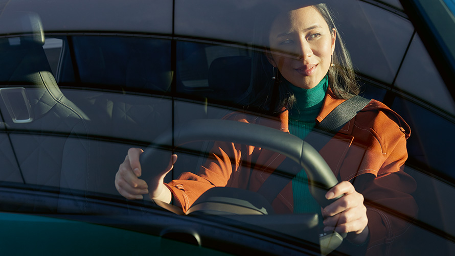 Moteris prie BMW vairo Moteris oranžiniu švarku prie BMW vairo